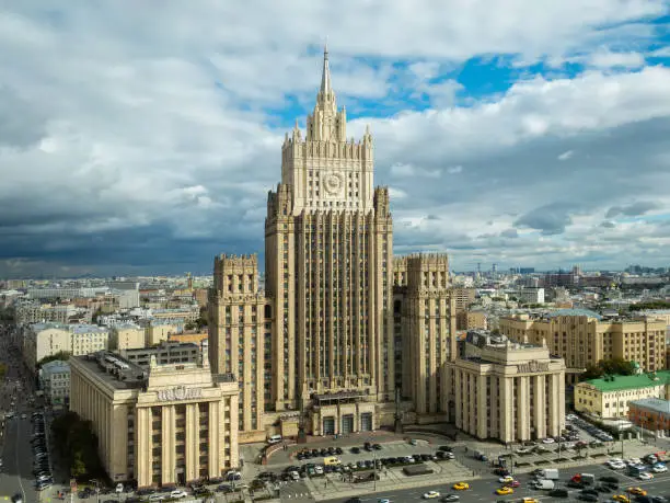 Photo of Moscow cityscape within day time. Offices buildings exterior. Building of the Ministry of Foreign Affairs  MFA. Rooftops of residential houses on blue sky, bottom up view coat of arms of the USSR
