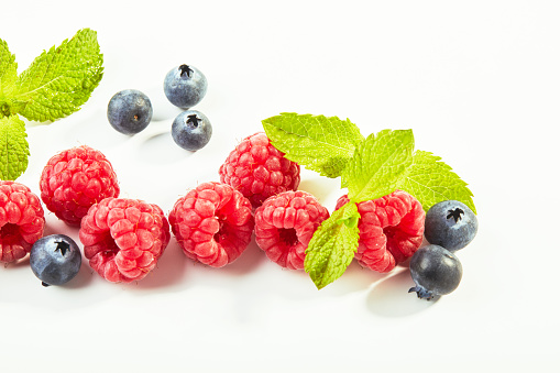 Raspberries and blueberries on white background