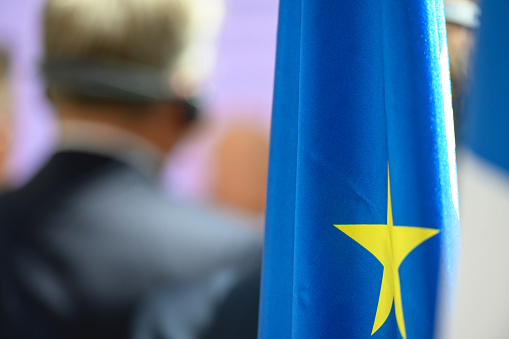 Folded flag of the European Union, rear view of unrecognizable politician in background