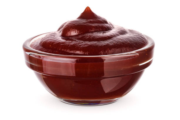 Bowl of barbecue sauce isolated on white. Barbecue sauce in glass transparent bowl, close-up. Isolated on white background. barbeque sauce photos stock pictures, royalty-free photos & images