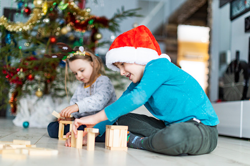 Children playing with wood blocks and building well with Christmas tree at background