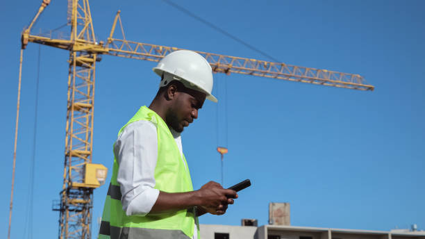 istock African American builder types report on smartphone by crane 1426672326