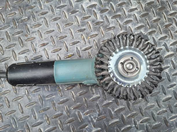 Electric rotating wire brush grinder on a metal floor. Top view.