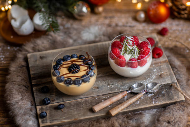 dessert de noël crème caramel et panna cotta aux baies fraîches dans la cuisine en bois rustique et les lumières de noël - bavarian cream photos et images de collection