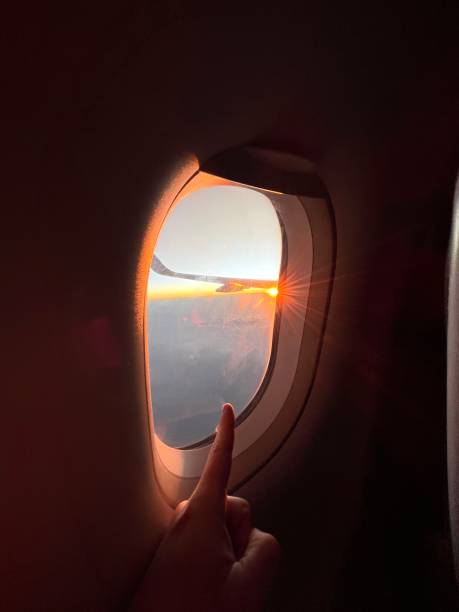 pov point de vue d’un jeune homme pointé du doigt à l’intérieur d’un avion devant la fenêtre, regardant le coucher / lever du soleil à l’horizon, attendant son temps de vacances. - aircraft point of view photos et images de collection