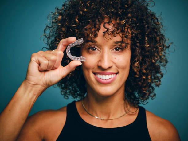 Smiling Woman Holding an Invisible Teeth Aligner stock photo