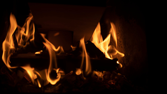 Firewood burning in fire. Flame in furnace. Hearth in house. Fireplace details. Yellow light.