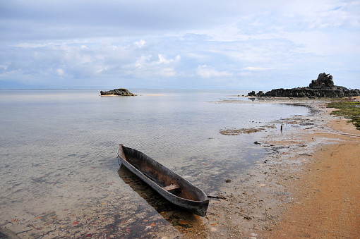 Dili Municipality, East Timor / Timor Leste: Hera Beach, aka Pasir Putih beach, named in Bahasa Indonesia for its white sand. Costal rock outcrops and pirogue - Banda Sea.