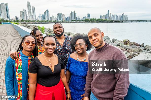 Portrait Of Cheerful Smiling Fashionable Afrodescendant Black Tourists Standing Together At Plaza V Centenario With A Skyline Evening View Of Panama City Stock Photo - Download Image Now