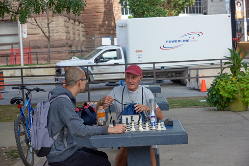 Toronto Ontario, Canada- September 20th, 2022: Two males taking with a chess game set up on a table.