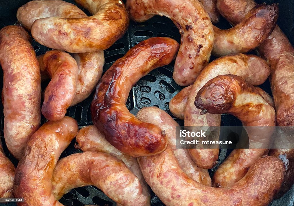 Full frame image of browning, pork sausages cooked in air fryer, healthier alternative to frying pan cooking, elevated view Stock photo showing close-up, elevated view of browning, pork sausages being cooked in an air fryer for healthier eating alternative to being fried in a frying pan. Air Fryer Stock Photo