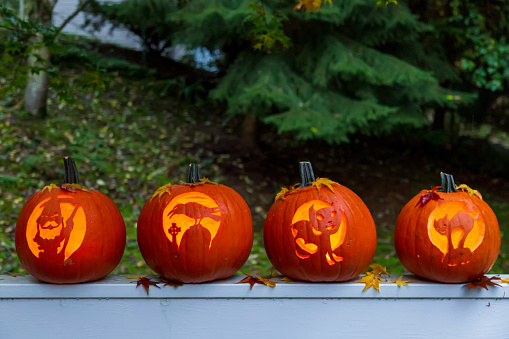 Four Halloween Jack O'Lantern pumpkins glowing in the dark