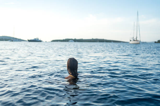 Young woman swims in sea at sunset