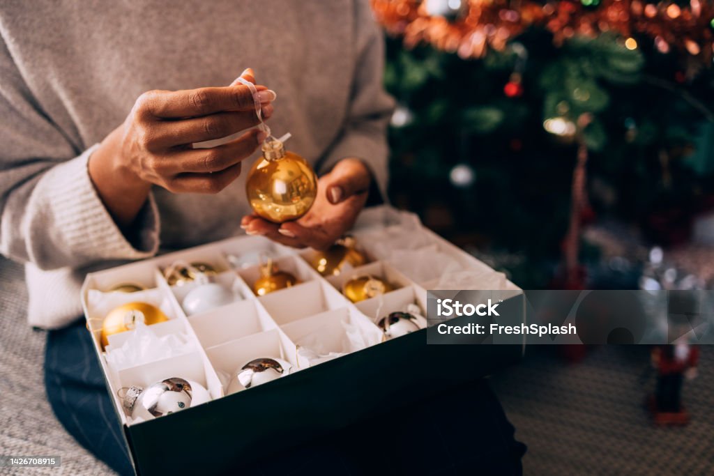Woman Holding A Bauble Anonymous woman holding a bauble in her hand, ready to do Christmas decorating. Christmas Ornament Stock Photo