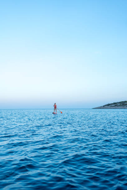 istock Young woman paddles SUP on sea 1426709607
