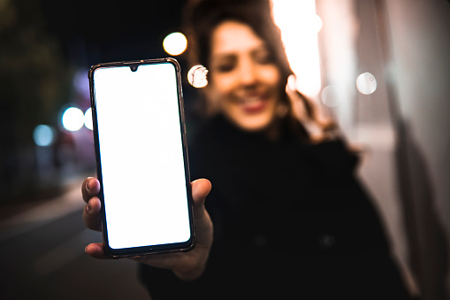 Picture of a caucasian girl showing phone while smiling