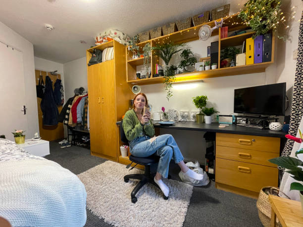 istock Image of fresher's university student moved into university accommodation bedroom office, redheaded woman sat in office chair eating a wrap sandwich, looking at camera 1426714473