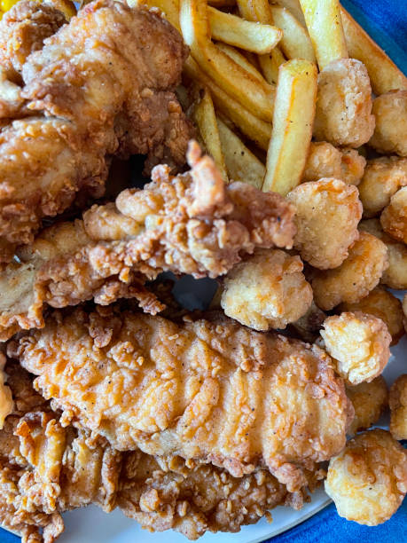 istock Full frame image of blue rimmed plate containing Southern fried chicken fillets, popcorn chicken pieces and chips, battered chicken breast pieces and French fries, elevated view 1426714974