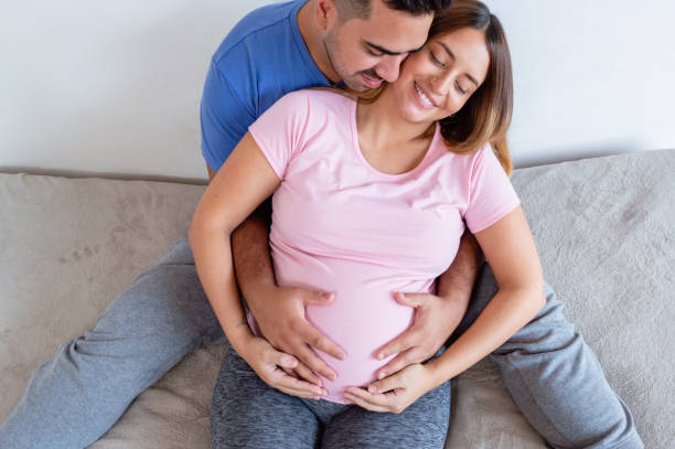 top view pregnant couple hugging sitting in bed stock photo