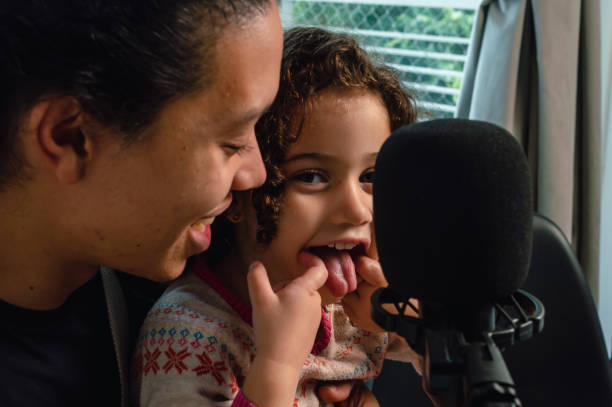 little girl sticking out her tongue looking at the camera happy with her dad in the music studio. stock photo