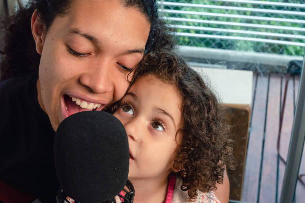 close-up happy father and daughter singing with a microphone indoors stock photo
