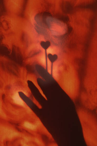 istock Blurred shadow of hand on red orange wall background with two hearts. Abstract, light and shadow.  Atmospheric mood and wellbeing. Valentines Day, Love, intimate, Couple relationship concept 1426724187