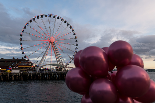 Seattle, USA - Apr 30, 2020. Late in the day a heart illuminated on the Seattle Ferris Wheel on the waterfront with graduation balloons.