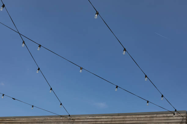 istock Strings of wires with lightbulbs against a blue sky, creative copy space background 1426728132