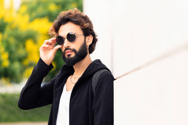 istock man putting on sunglasses leaning in a white wall 1426729596