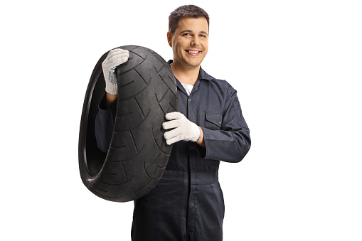 Auto mechanic holding a motorcycle tire isolated on white background