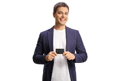 Smiling young man holding a credit card isolated on white background