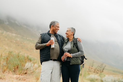 Senior couple hiking in the mountains in nature, walking for fitness on holiday in mountain and exercise during vacation in the countryside together. Happy latino man and woman on walk for health