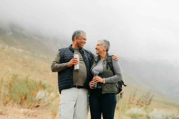 Senior couple hiking in the mountains in nature, walking for fitness on holiday in mountain and exercise during vacation in the countryside together. Happy latino man and woman on walk for health stock photo