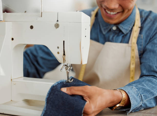 istock Design student, creative and worker in a studio sewing clothes and garments. Fashion student learning sewing machine skills in a textile and manufacturing studio. Happy trainee practicing his craft 1426755487