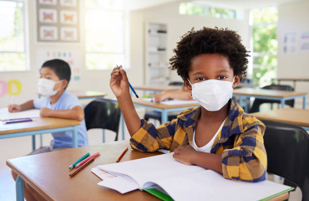 istock Child or student in class during covid, wearing a mask for hygiene and protection from coronavirus flu. Portrait kindergarten, preschool or elementary school boy sitting in a classroom ready to learn 1426755517