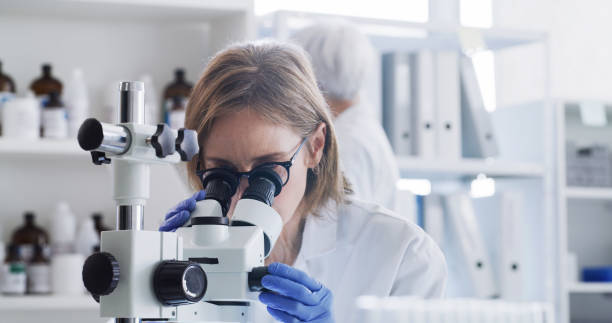 Woman, microscope or laboratory study for covid vaccine, future medicine or healthcare wellness. Doctor, dna engineer or medical research scientist in cancer science analytics or insurance innovation stock photo