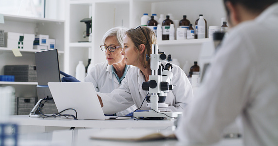 Science, medicine and research, women in laboratory with laptop and equipment. Woman scientist, doctor or pharmacist checking data and lab work online. Technology and medical innovation in healthcare