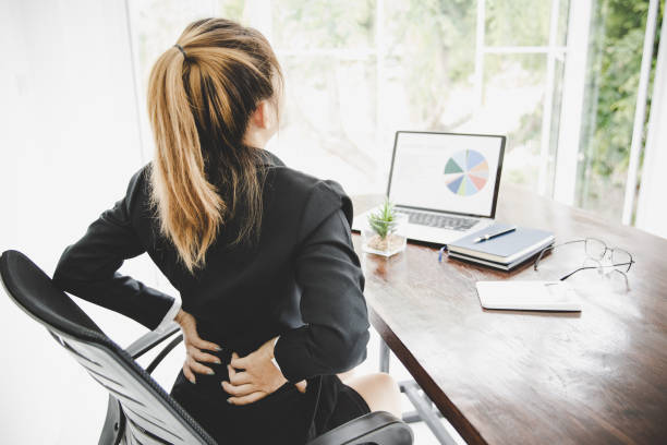 jeune femme d’affaires au bureau avec de terribles maux de dos - orthèse photos et images de collection