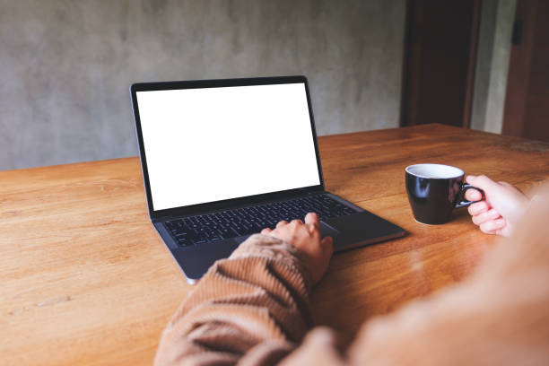 istock Mockup image of a woman using and typing on laptop computer with blank white desktop screen while drinking coffee 1426772112