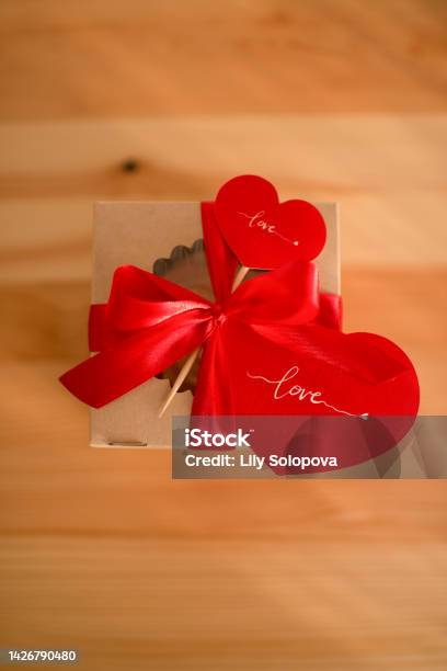 Tangan Menarik Pita Merah Pada Hadiah Yang Dibungkus Kertas Coklat Foto  Stok - Unduh Gambar Sekarang - iStock