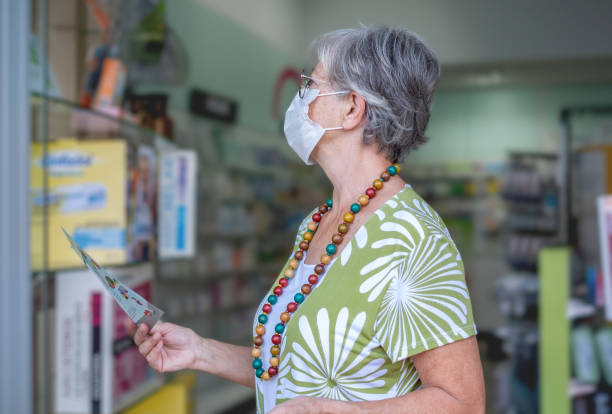 starsza kobieta nosząca maskę w sklepie aptecznym patrząca na produkty medyczne. portret przystojnej starszej pani w aptece drogeryjnej - vitamin pill store shopping senior adult zdjęcia i obrazy z banku zdjęć