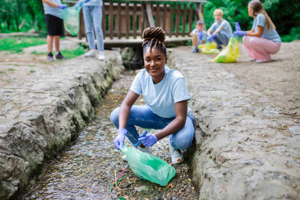 istock Woman handpicking gathering up garbage plastic straws garbage from the river at the park. World environment day.Environment concept. 1426804246