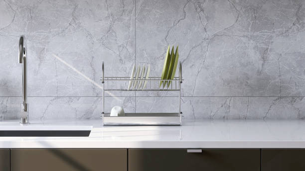 istock Modern and minimal built-in gray kitchen counter with white laminate top, sink and white marble tile wall in sunlight from window 1426824551