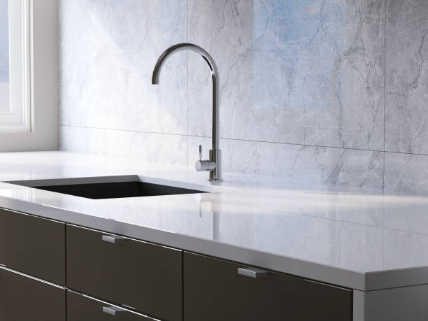 istock Modern and minimal built-in gray kitchen counter with white laminate top, sink and white marble tile wall in sunlight from window 1426824564