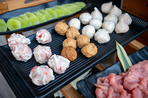 Raw seafood and meat meatballs with luxury hot pot ingredients arranged and prepared to be cooked in a boiling soup in hot pot style Chinese restaurant