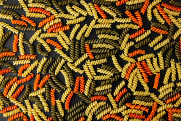 Raw pasta torti pattern on black background.
