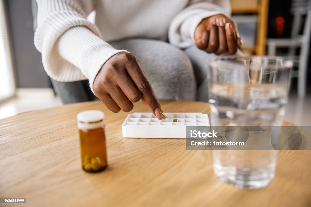 Woman filling daily pill container with prescription medications Woman filling daily pill container with prescription medications. 25-29 Years Stock Photo