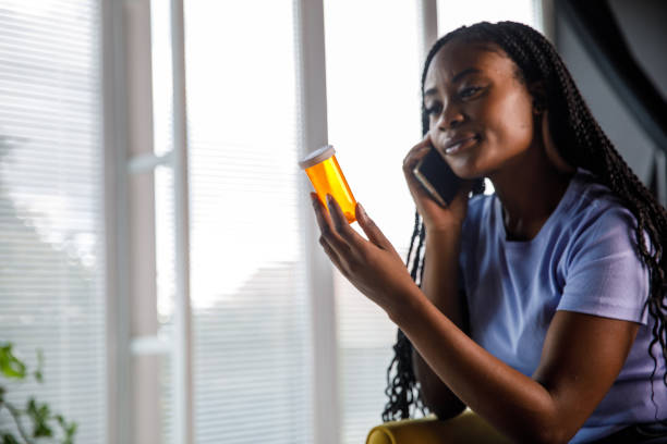 istock Young woman talking on the phone and studying a pill bottle label 1426832222