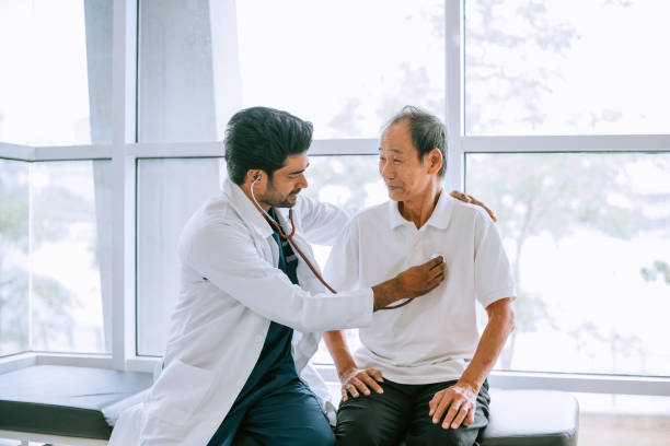 aufnahme eines arztes, der einen patienten während einer konsultation in einem krankenhaus mit einem stethoskop untersucht - asian ethnicity doctor patient healthcare and medicine stock-fotos und bilder