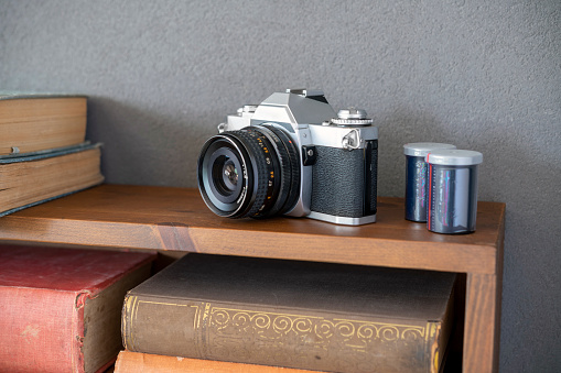 Old fashioned 35mm camera with slide film on bookshelf